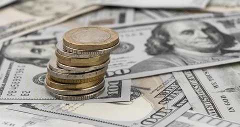 Stack of golden coins on dollar bills on a table. Stock Photos