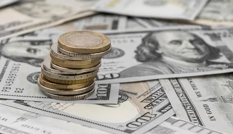 Stack of golden coins on dollar bills on a table. Stock Photos