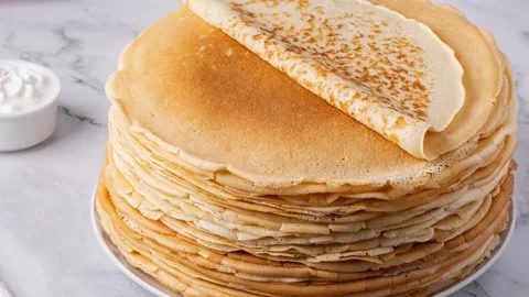 Stack of golden crepes served with sour cream. High quality 4k footage Stock Footage 325483988