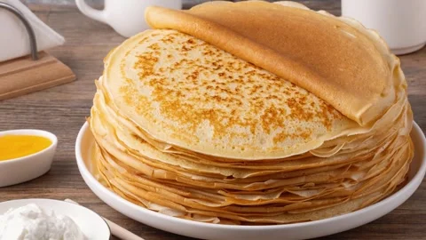 Stack of golden crepes served with sour cream on a wooden table Stock Footage 329448171