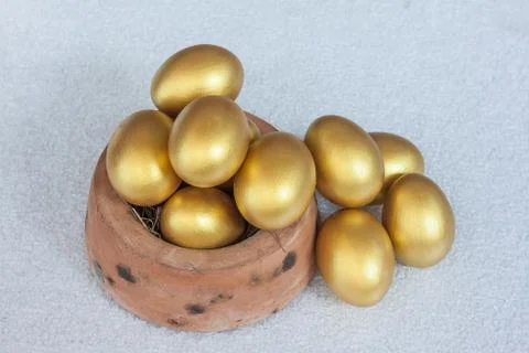 Stack of golden easter egg in baked clay bowl Stock Photos