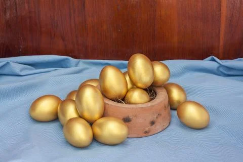 Stack of golden easter egg in baked clay bowl Stock Photos