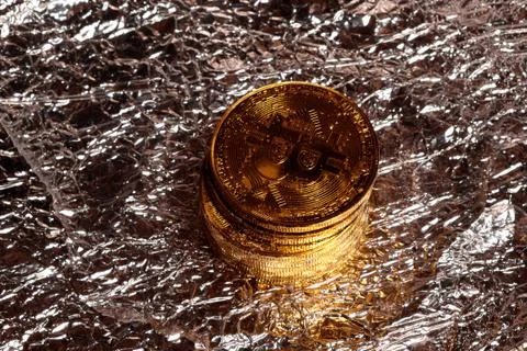 Stack of golden physical bitcoins on a foil background Foto stock