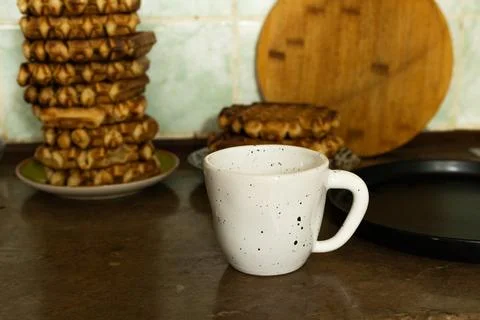 Stack of golden waffles and a speckled mug on a kitchen counter Foto stock