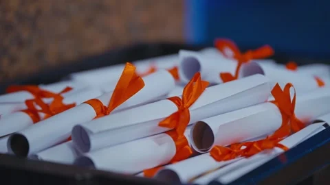 Stack of Graduation Diplomas Tied with Orange Ribbons Ready for Ceremony Stock Footage 321013967