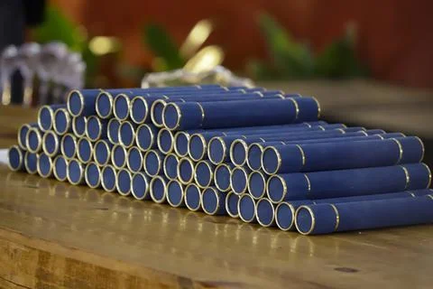A stack of graduation tubes on a wooden table, predominantly blue with a sued Stock Photos
