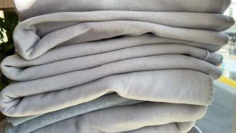 Stack of gray blankets smooth out a stack of folded sheets and place a pink Stock Footage 317053896