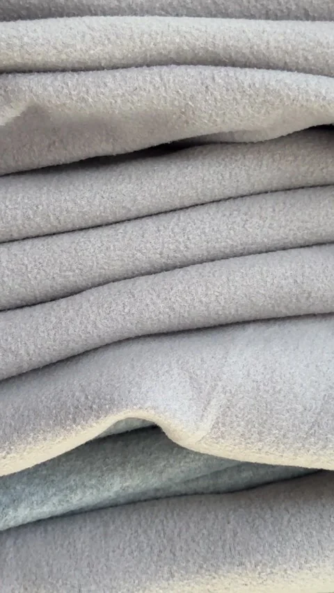 Stack of gray blankets smooth out a stack of folded sheets and place a pink Stock Footage 323286139
