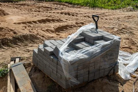A stack of gray bricks is wrapped in plastic at a construction site Stock Photos