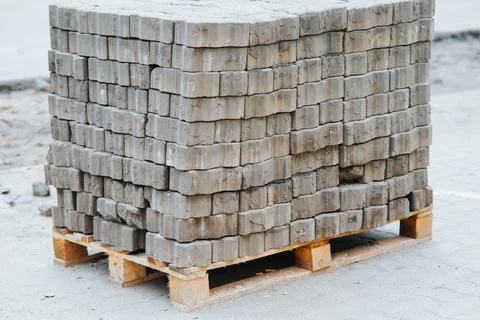 A stack of gray concrete blocks is placed on wooden pallets. This setup is Stock Photos