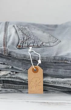 Stack of gray jeans and tag with inscription free on white background Stock Photos