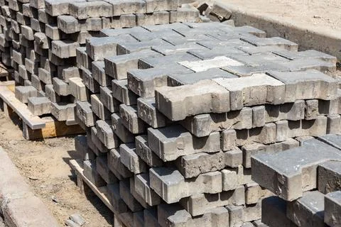 Stack of gray paving stones arranged neatly at a construction site on a sunny Stock Photos
