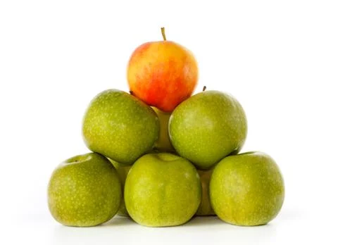 Stack of green apples and one yellow with red blush on top Stock Photos