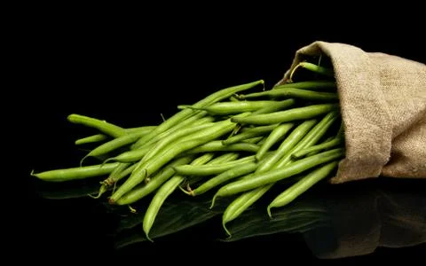 Stack of green beans in linen sack on black Stock Photos