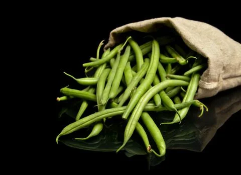 Stack of green beans in linen sack on black background Stock Photos