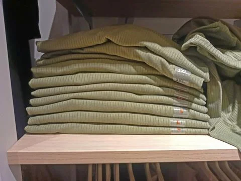 A stack of green clothes is on a shelf in a supermarket Foto stock