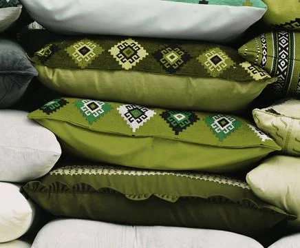 A stack of green pillows with an ornament. Handmade pillow sale on the street Stock-Fotos