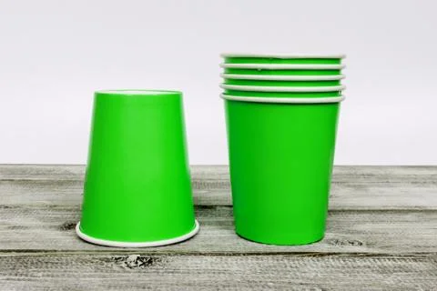 A stack of green take away disposable paper cups on wooden desk with white ba Stock Photos