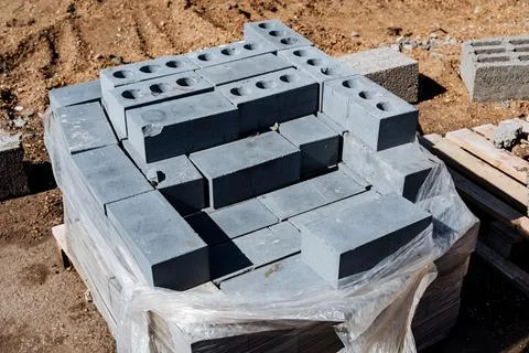 Stack of grey concrete blocks neatly stacked on construction site, wrapped .. Stock Photos
