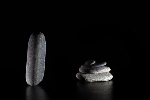 Stack of grey massage stones on dark grey background Stock Photos