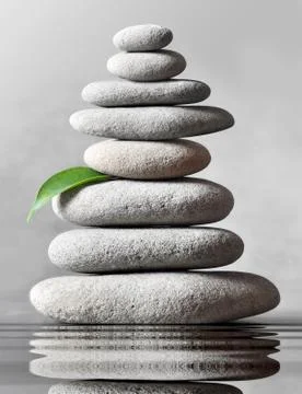 Stack of grey massage stones on grey background. Stock Photos