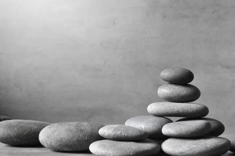 Stack of grey massage stones on grey background. Stock Photos