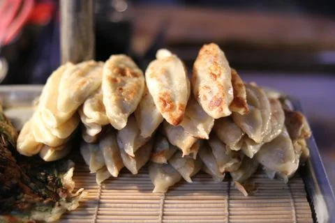 Stack of gyoza or pan fried dumplings on display for sale on street Stock Photos