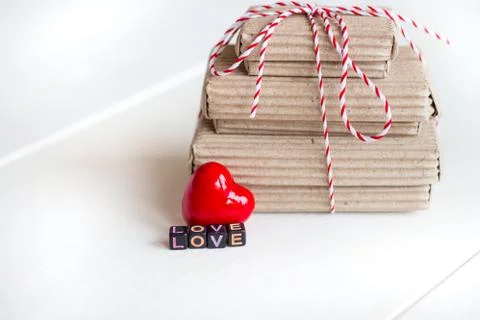 Stack of handcraft gift boxes on white wooden background with red heart Stock Photos