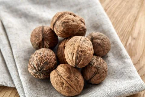 A stack of hard shells of walnuts piled together on light grey fabric cotton Stock Photos
