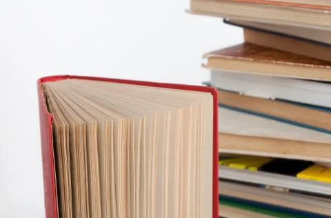 Stack of hardback books and old open book on white wall background. Search for Stock Photos