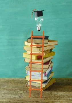 Stack of hardback books with college hat and lightbulb. Learning,education,.. Stock Photos