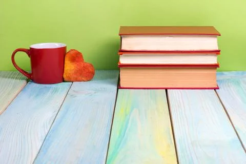 Stack of hardback books, diary on wooden deck table and green background. Back Foto stock
