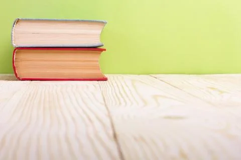 Stack of hardback books, diary on wooden deck table and green background. Back Stock Photos