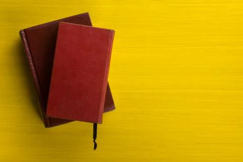 Stack of hardback books, diary on wooden deck table and yellow background. Back Foto stock