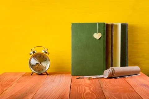 Stack of hardback books, diary on wooden deck table and yellow background. Back Stock-Fotos