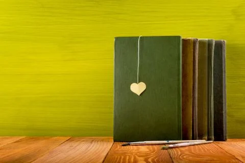 Stack of hardback books, diary on wooden deck table and green background. Back Stock Photos
