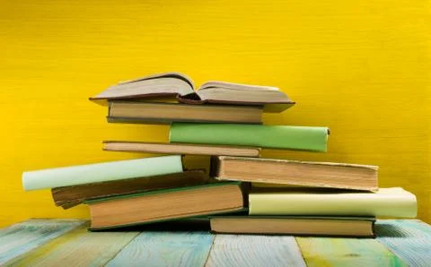 Stack of hardback books, diary on wooden deck table and yellow background. Back Stock-Fotos