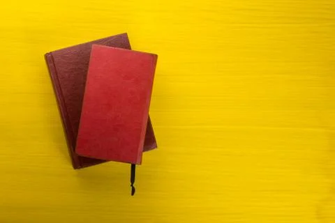 Stack of hardback books, diary on wooden deck table and yellow background. Back Stock Photos