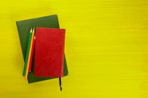 Stack of hardback books, diary on wooden deck table and yellow background. Back Foto stock