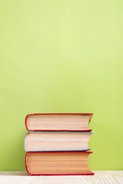 Stack of hardback books, diary on wooden deck table and green background. Back Stock-Fotos