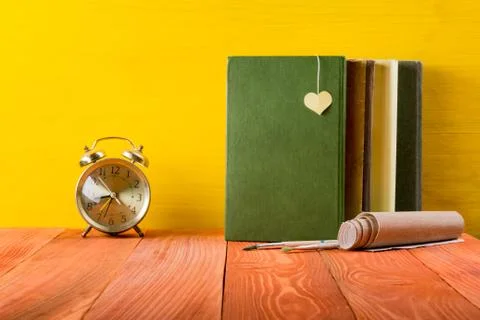 Stack of hardback books, diary on wooden deck table and yellow background. Back Stock Photos