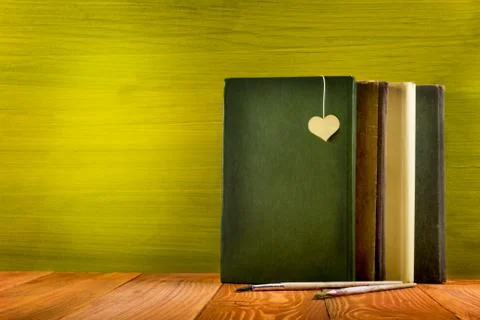 Stack of hardback books, diary on wooden deck table and green background. Back Stock Photos