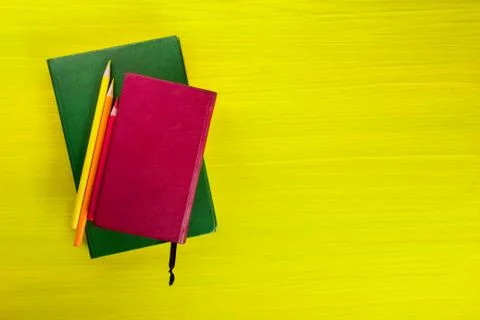 Stack of hardback books, diary on wooden deck table and yellow background. Back Stock-Fotos