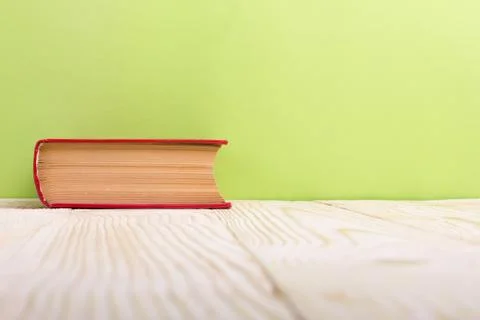 Stack of hardback books, diary on wooden deck table and green background. Back Stock Photos