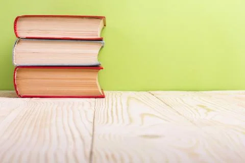 Stack of hardback books, diary on wooden deck table and green background. Back Stock-Fotos