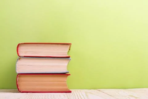 Stack of hardback books, diary on wooden deck table and green background. Back Stock Photos