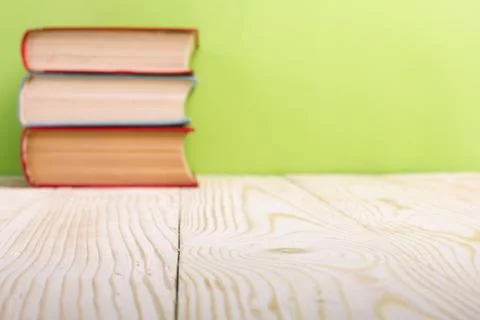 Stack of hardback books, diary on wooden deck table and green background. Back Stock-Fotos