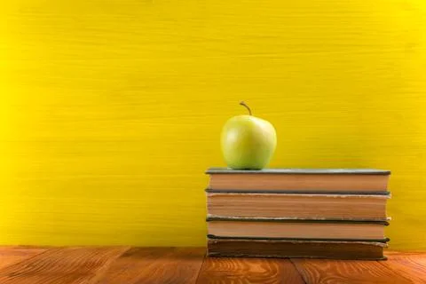 Stack of hardback books, diary on wooden deck table and yellow background. Back Foto stock