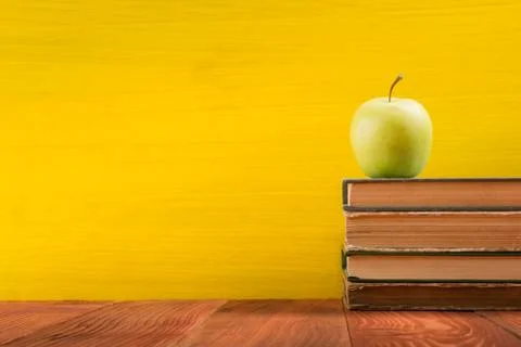 Stack of hardback books, diary on wooden deck table and yellow background. Back Stock Photos