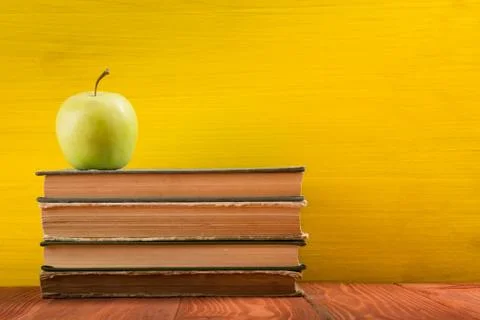 Stack of hardback books, diary on wooden deck table and yellow background. Back Stock Photos
